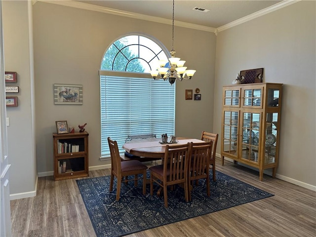 dining room with baseboards, visible vents, a notable chandelier, wood finished floors, and crown molding