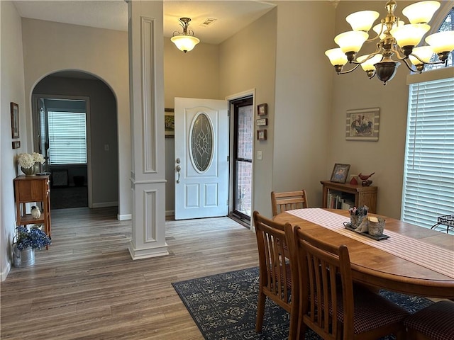 dining room with baseboards, wood finished floors, arched walkways, and a notable chandelier