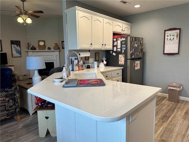 kitchen featuring a peninsula, freestanding refrigerator, light wood finished floors, and a ceiling fan