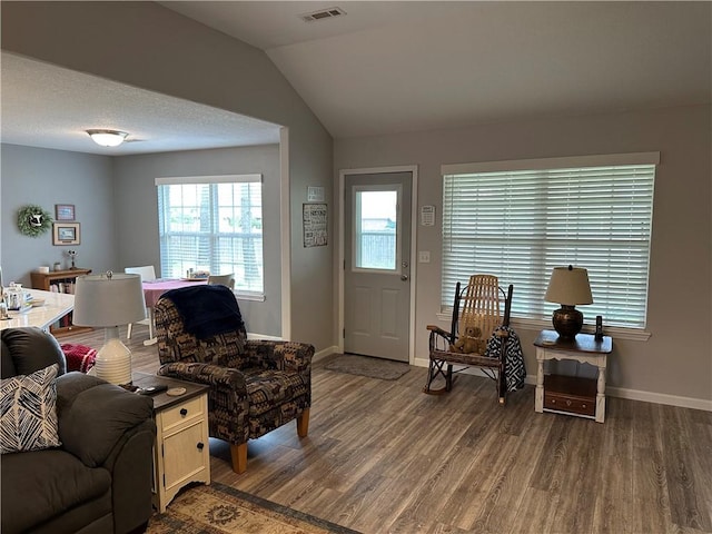 living area featuring dark wood-style floors, baseboards, lofted ceiling, and visible vents