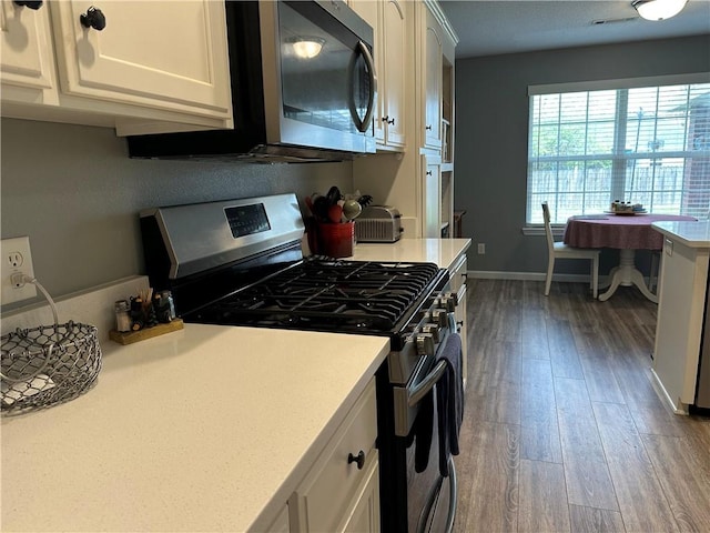 kitchen with light countertops, wood finished floors, white cabinets, and stainless steel appliances