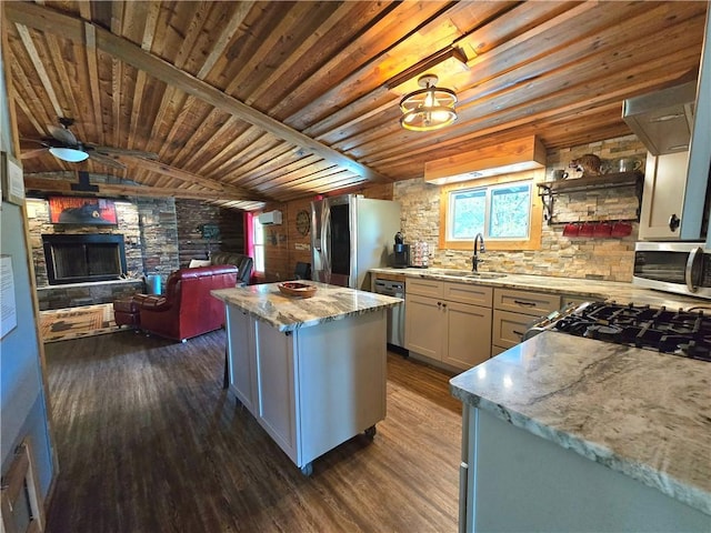 kitchen with a sink, open floor plan, dark wood finished floors, appliances with stainless steel finishes, and a kitchen island