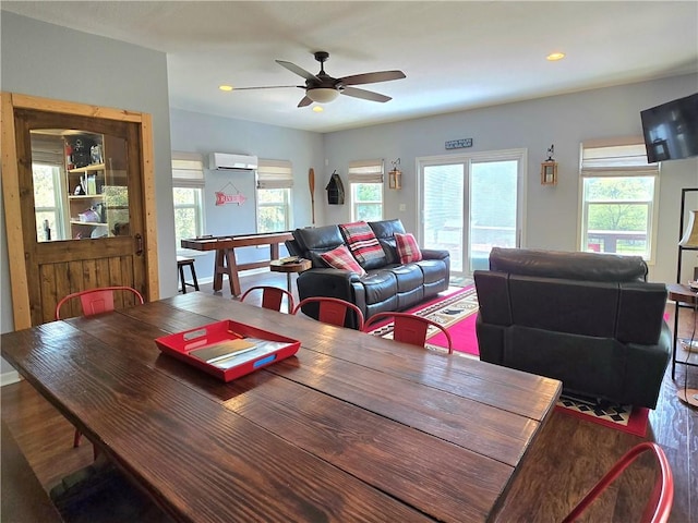 dining area featuring a ceiling fan, wood finished floors, a wealth of natural light, and a wall unit AC