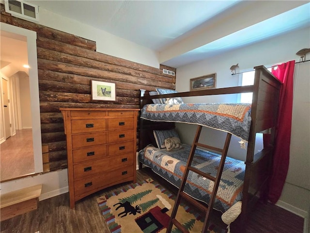 bedroom featuring baseboards, visible vents, rustic walls, and dark wood-style flooring