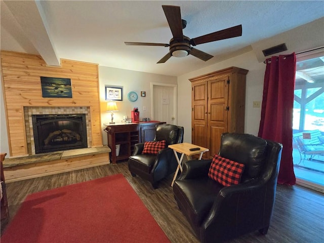 living room featuring dark wood-type flooring, a tile fireplace, visible vents, and ceiling fan