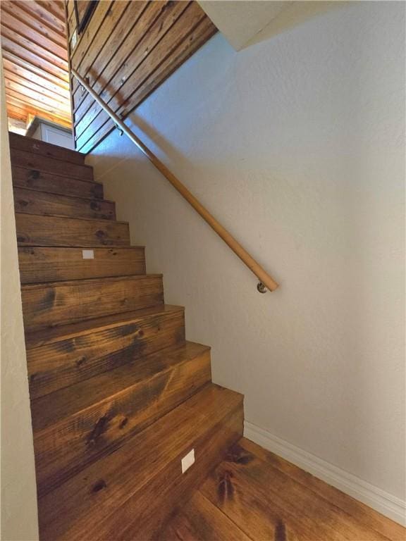stairway with wood finished floors and baseboards