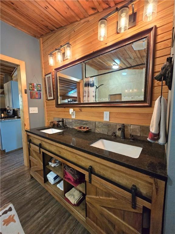 full bathroom featuring wood ceiling, wood finished floors, a sink, and double vanity