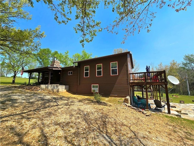 view of side of home featuring a chimney, stairway, a patio area, and a deck