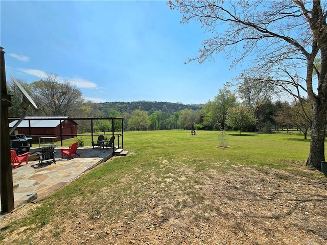 view of yard with a view of trees and a patio