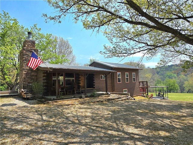 rear view of property featuring a chimney and metal roof