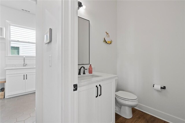 bathroom featuring toilet, vanity, and baseboards