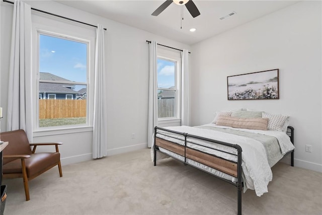 bedroom with multiple windows, light carpet, and baseboards