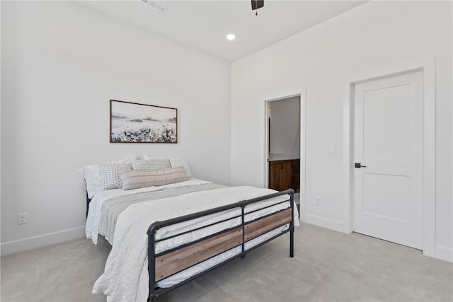 bedroom featuring light colored carpet, baseboards, a ceiling fan, and ensuite bath