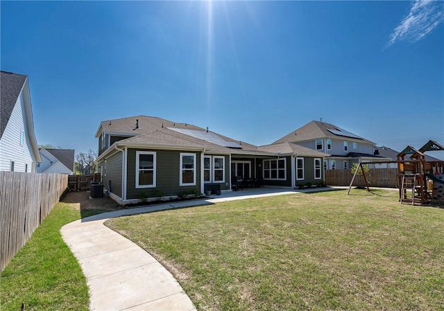 rear view of property with a playground, central air condition unit, a patio area, and solar panels