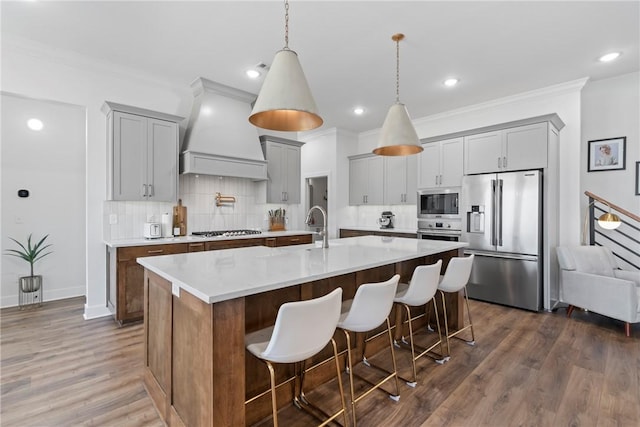 kitchen featuring appliances with stainless steel finishes, custom exhaust hood, gray cabinets, ornamental molding, and tasteful backsplash