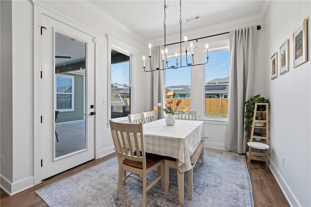 dining space with a chandelier, dark wood-style floors, crown molding, and baseboards