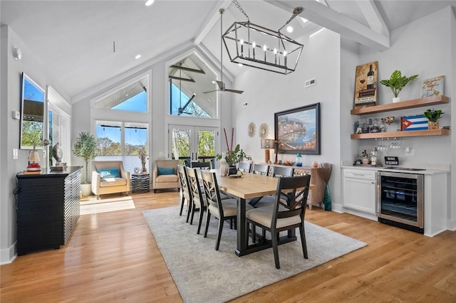 dining room with plenty of natural light, beverage cooler, a bar, and high vaulted ceiling