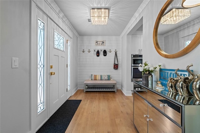 entryway featuring baseboards, a notable chandelier, and light wood-style flooring