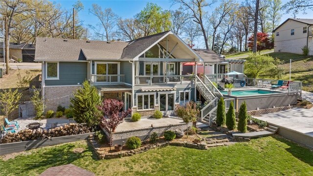 back of property with a lawn, brick siding, a patio, and a fenced in pool