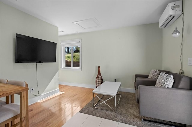 living room with attic access, wood finished floors, an AC wall unit, and baseboards