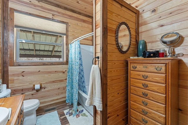full bath with vanity, shower / tub combo with curtain, wooden walls, toilet, and visible vents