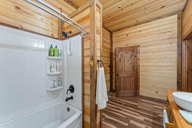 bathroom featuring vanity, wood finished floors, shower / tub combination, and wooden walls