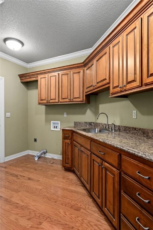 laundry area featuring a sink, hookup for an electric dryer, hookup for a washing machine, cabinet space, and ornamental molding