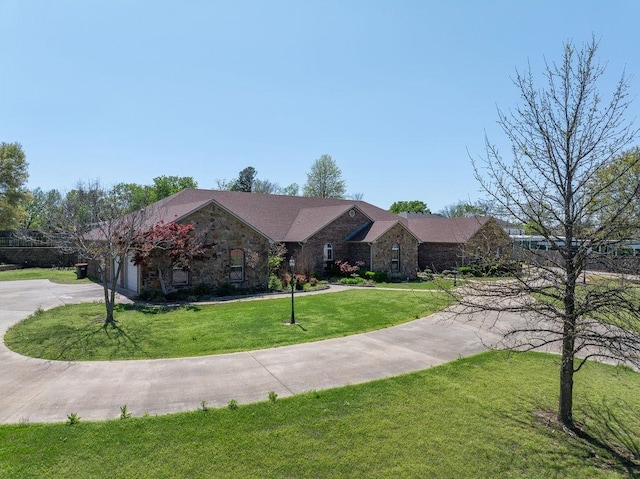 ranch-style house with concrete driveway, an attached garage, stone siding, and a front yard