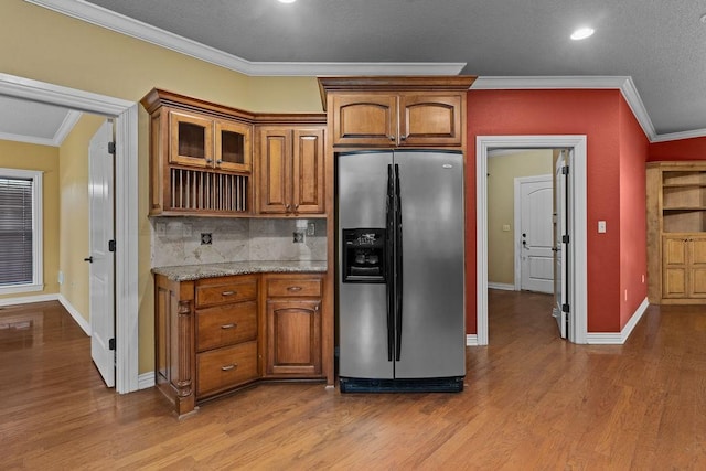 kitchen featuring brown cabinets, stainless steel fridge with ice dispenser, ornamental molding, and wood finished floors