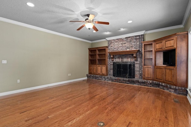 unfurnished living room featuring a textured ceiling, baseboards, a ceiling fan, wood finished floors, and a brick fireplace