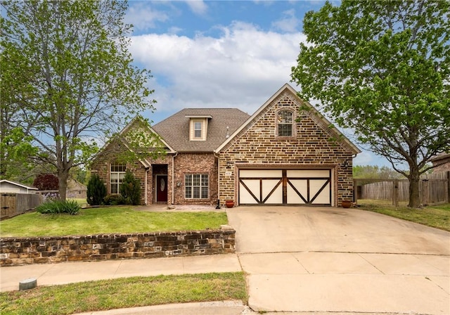 craftsman inspired home featuring roof with shingles, driveway, fence, brick siding, and a front yard