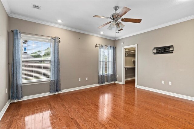 empty room featuring wood finished floors, a wealth of natural light, a ceiling fan, and baseboards