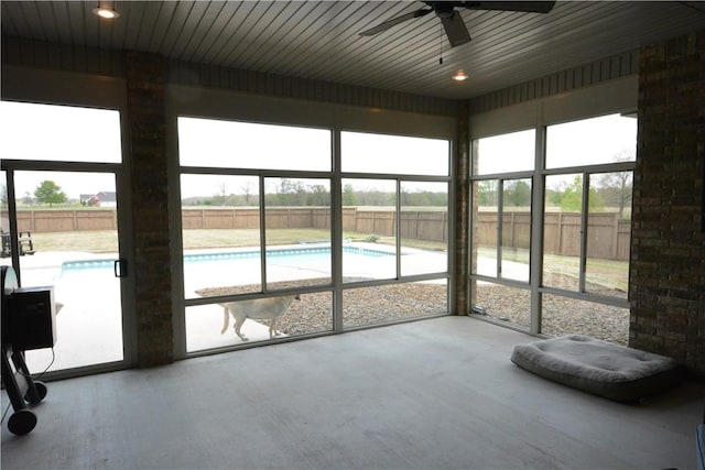 unfurnished sunroom featuring a ceiling fan and a wealth of natural light