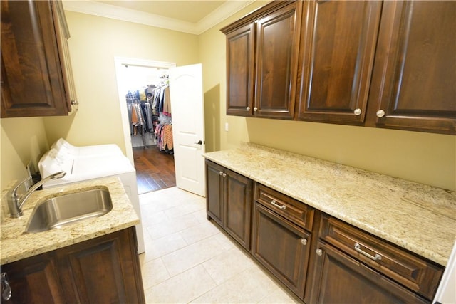 clothes washing area featuring ornamental molding, a sink, light tile patterned flooring, washer and dryer, and cabinet space
