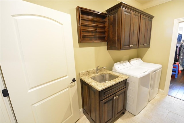 washroom featuring a sink, light tile patterned flooring, washing machine and clothes dryer, baseboards, and cabinet space