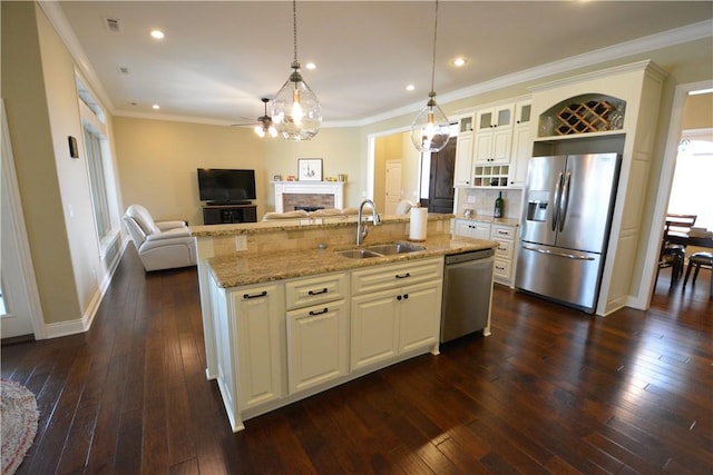 kitchen featuring a ceiling fan, a sink, open floor plan, stainless steel appliances, and a center island with sink