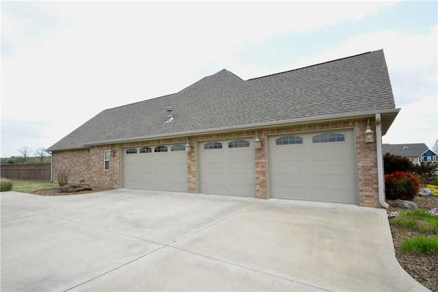 view of property exterior featuring brick siding, a shingled roof, and concrete driveway
