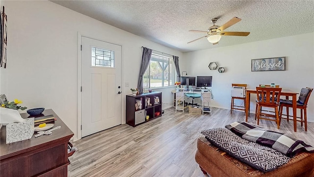 living room featuring a ceiling fan, a textured ceiling, and wood finished floors