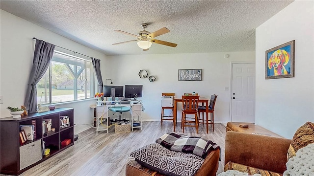 living room featuring a textured ceiling, ceiling fan, and wood finished floors