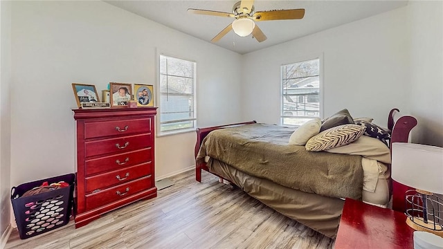 bedroom with baseboards, ceiling fan, wood finished floors, and multiple windows