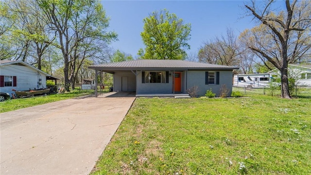 view of front of house featuring driveway, metal roof, a front yard, fence, and an attached carport