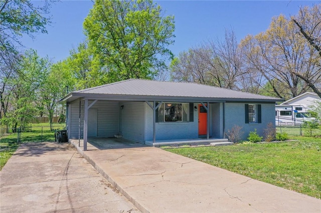 view of front of home featuring concrete driveway, a front lawn, fence, an attached carport, and metal roof