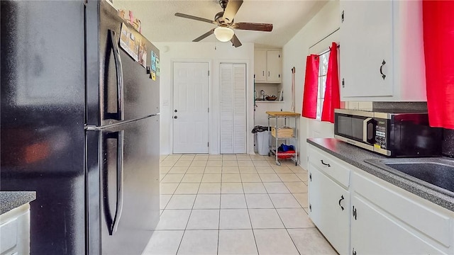 kitchen featuring freestanding refrigerator, white cabinetry, stainless steel microwave, a ceiling fan, and light tile patterned floors