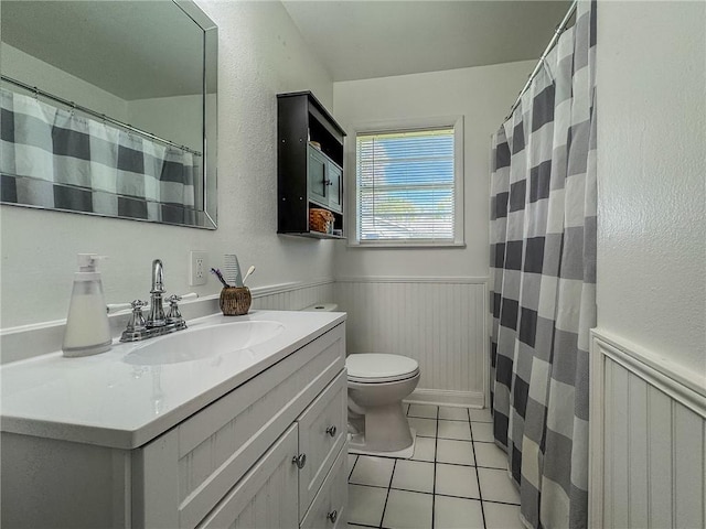 bathroom with tile patterned flooring, vanity, toilet, a wainscoted wall, and a shower with curtain