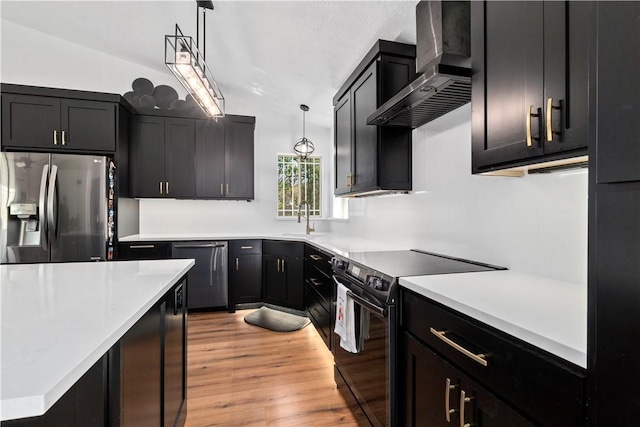 kitchen with wall chimney exhaust hood, stainless steel appliances, light wood finished floors, a sink, and light countertops