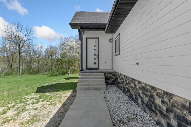 doorway to property with a yard and a shingled roof