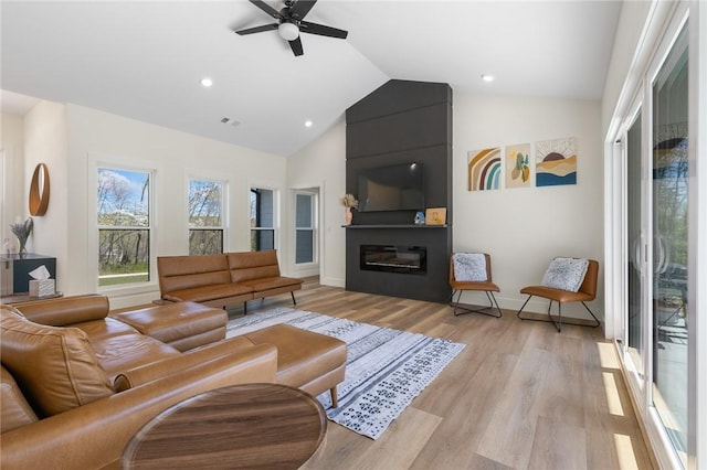 living area with light wood-style flooring, vaulted ceiling, baseboards, visible vents, and a ceiling fan