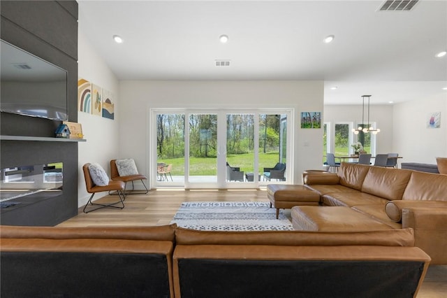 living area with an inviting chandelier, wood finished floors, a wealth of natural light, and recessed lighting
