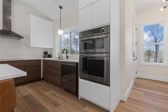 kitchen with white cabinets, modern cabinets, wall chimney range hood, dishwasher, and double oven