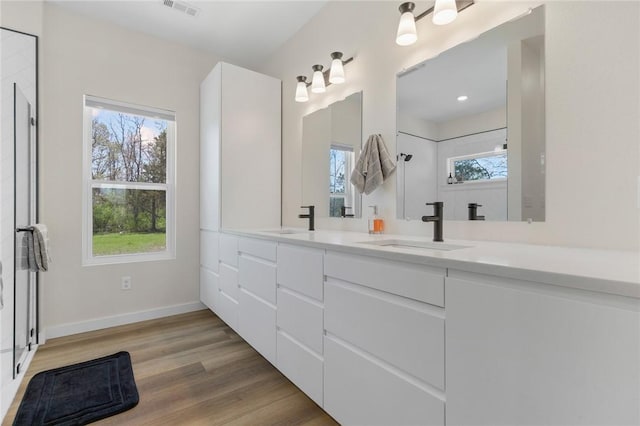 full bathroom featuring baseboards, wood finished floors, a sink, and visible vents